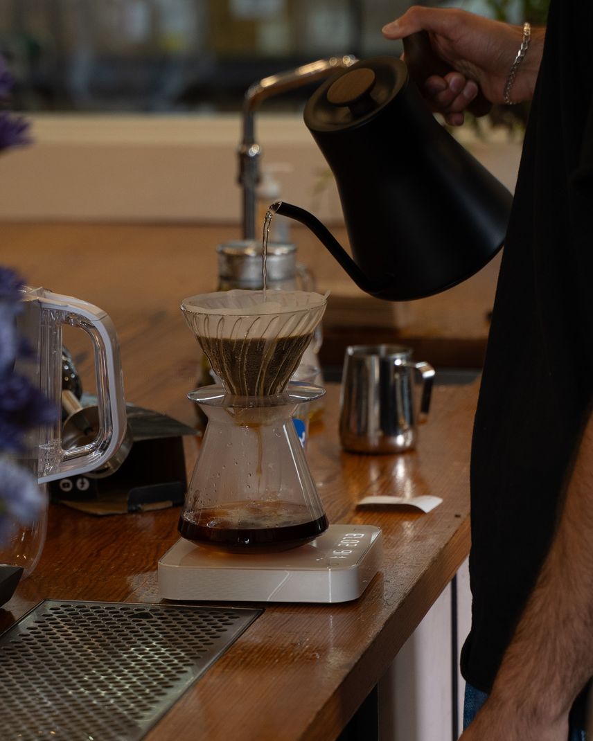 Barista brewing a pour-over coffee with a gooseneck kettle